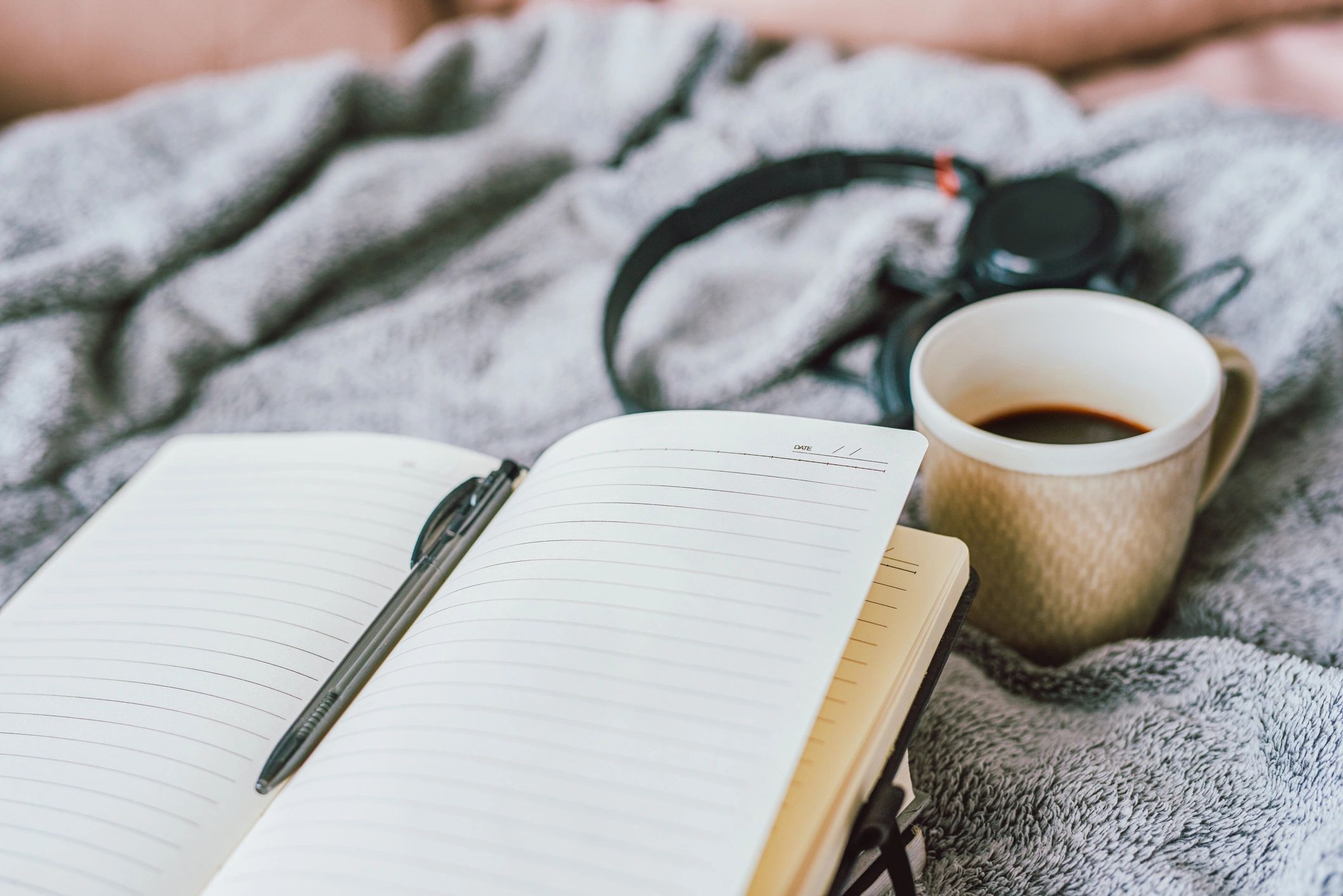 Notebook and coffee on a cozy bed setup