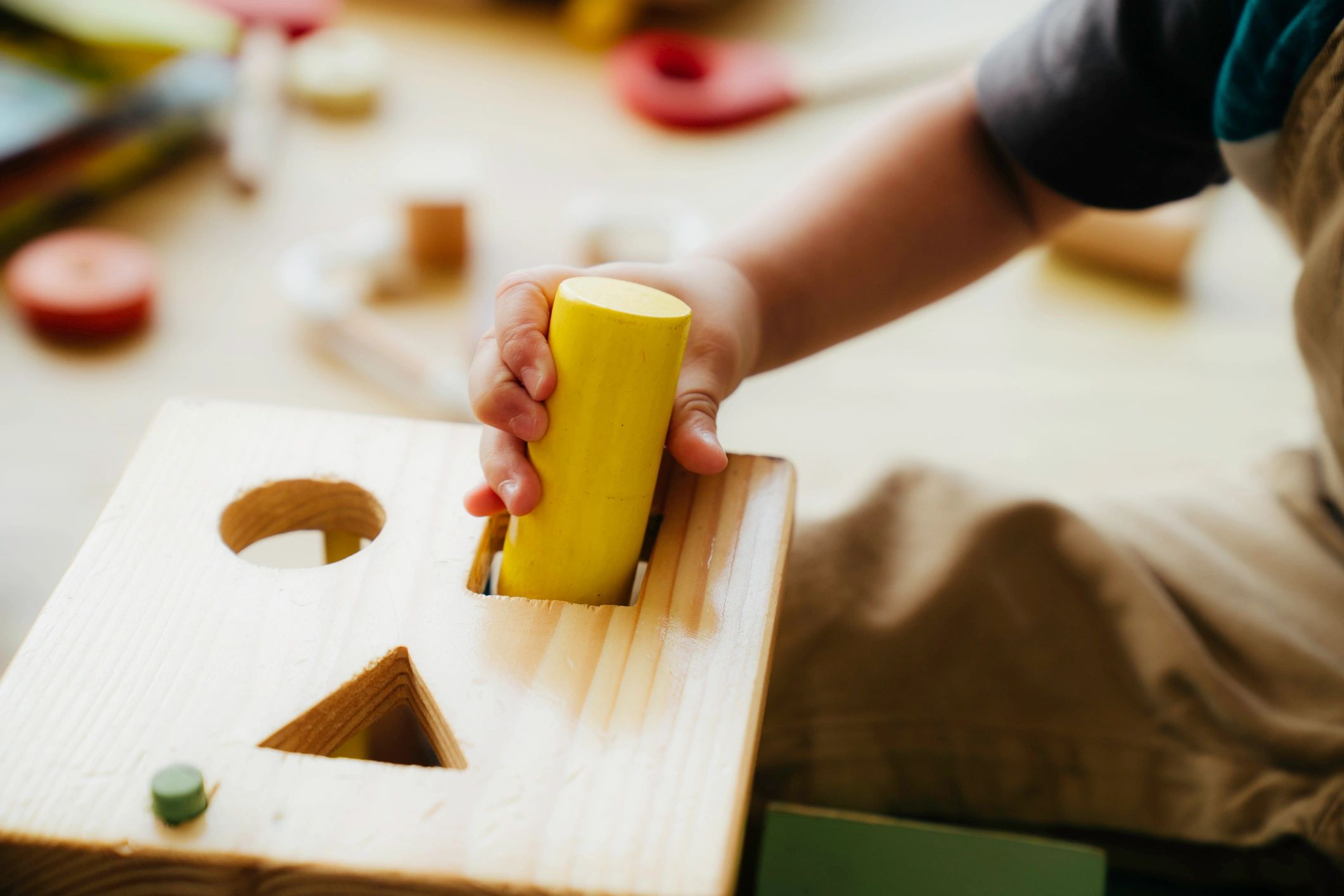 Child hands playing with a wooden toy block for sensory play