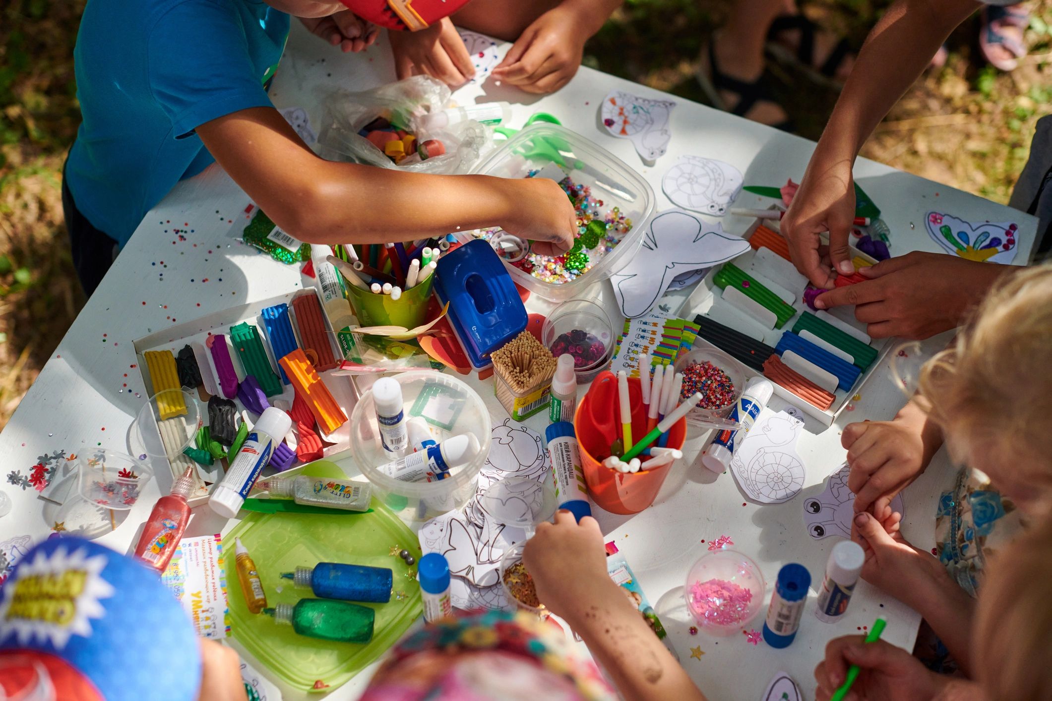 Kids crafting with parents at an outdoor party table