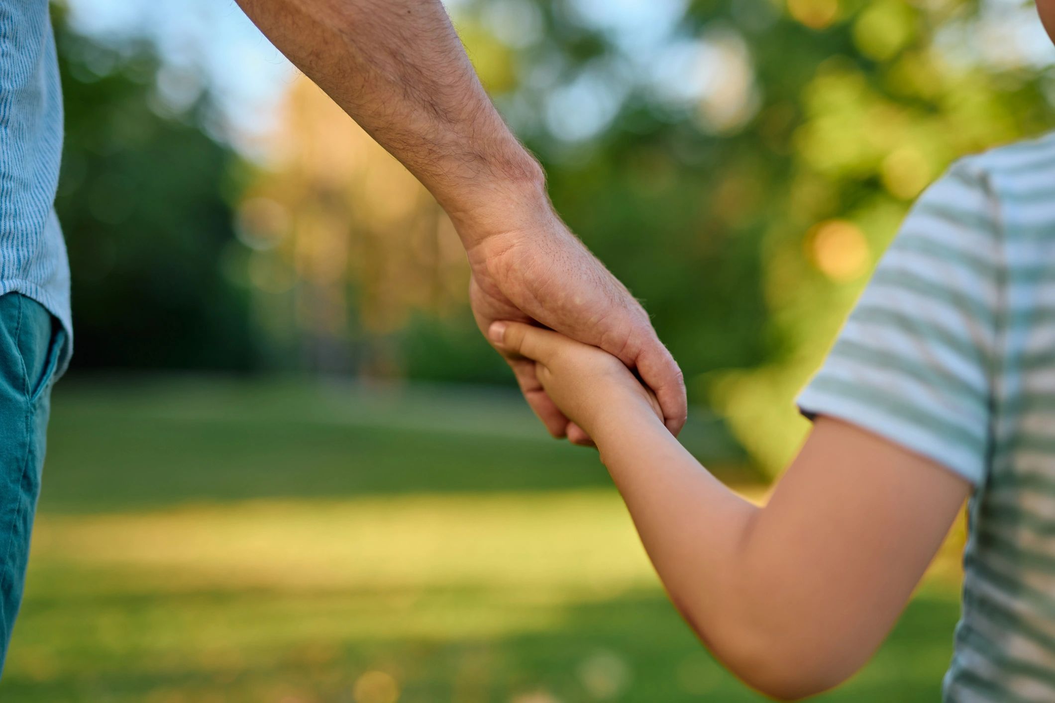 Adult and child holding hands on a nature walk